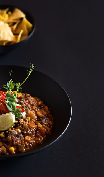 Zwei schwarze Teller mit Tortillachips und Dip